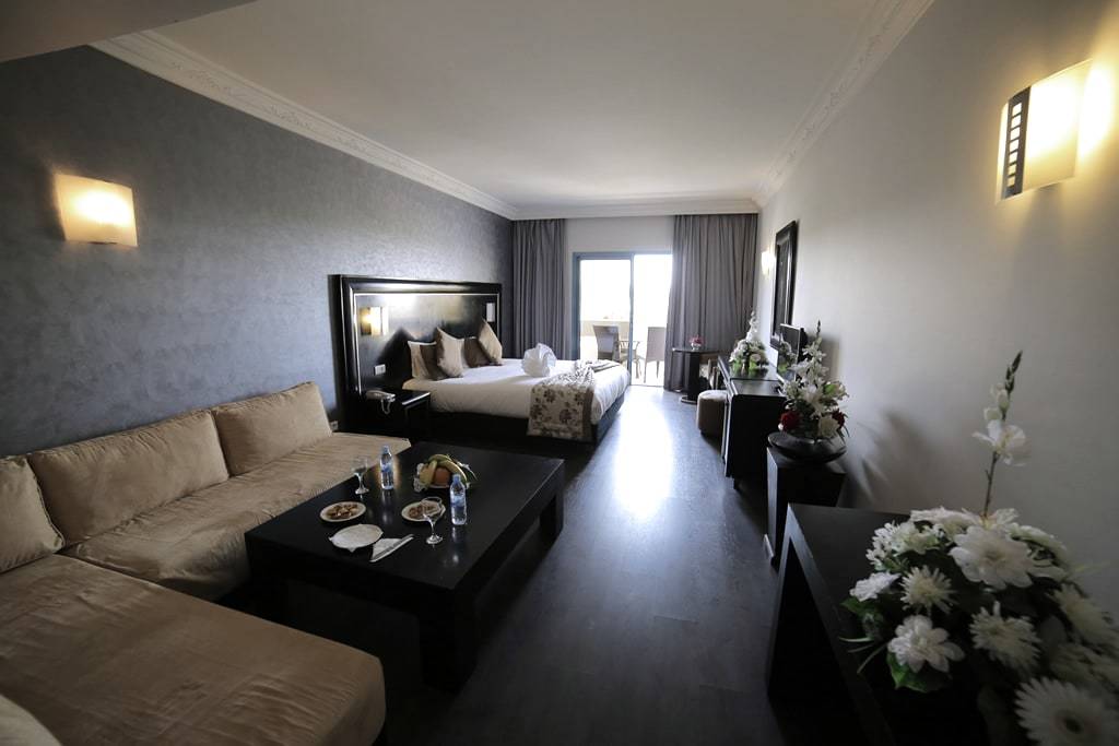 Salon de suite avec canapé, chambre en arrière-plan