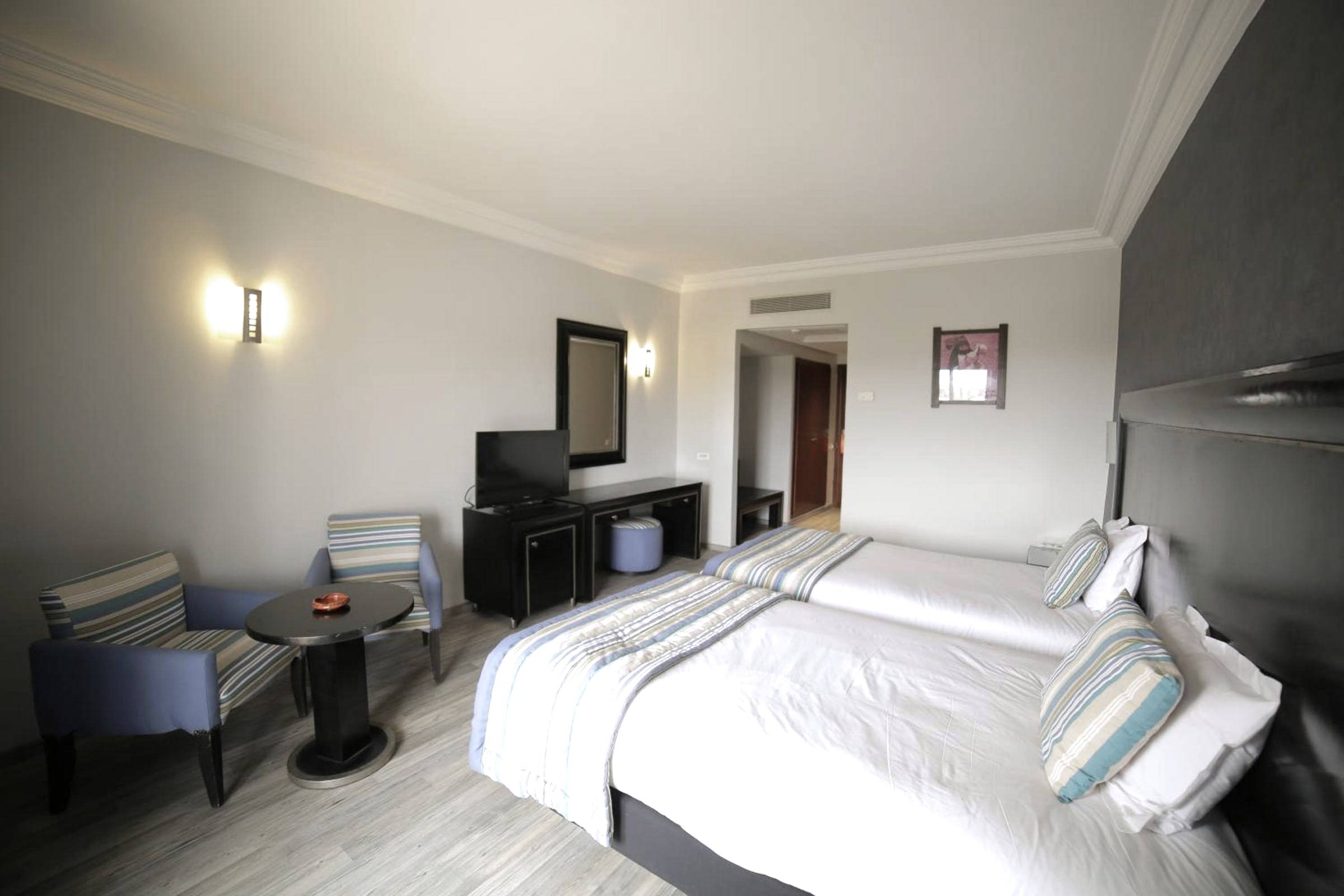 Chambre aux lits jumeaux, linge blanc, porte-fenêtre sur le balcon