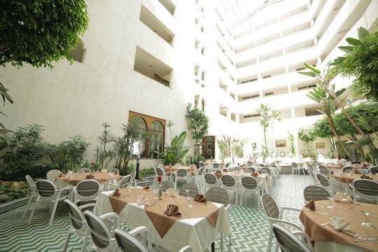 Le Patio vu du rez-de-chaussée : plantes, tables et balcons intérieurs.